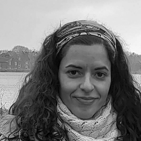 Head and shoulders photograph of a woman with shoulder-length curly hair wearing a woollen scarf