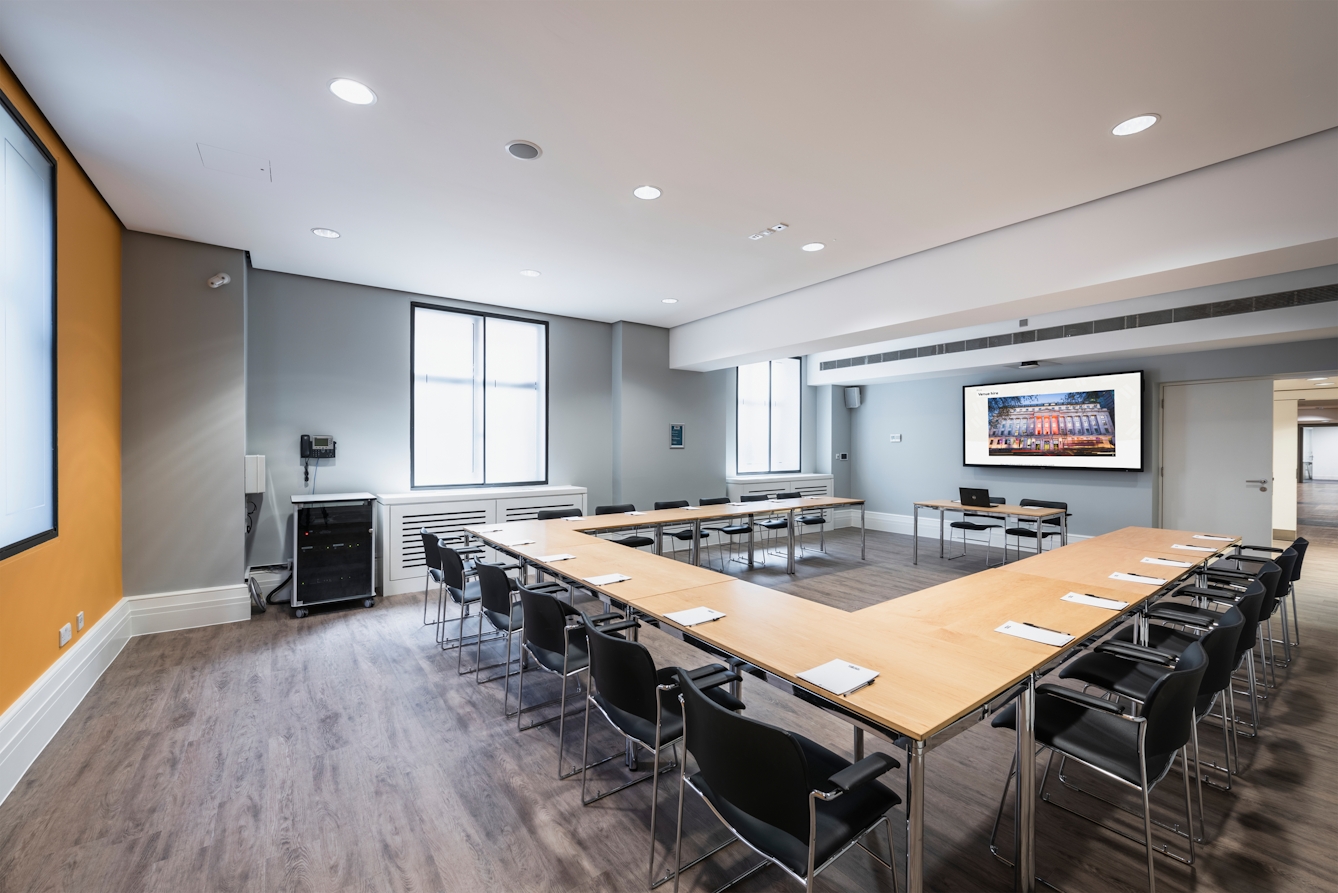 Photograph of the Dale room at the Wellcome Collection. 

Photograph shows a U-shape desk set-up and a presenting screen at the front of the room. 