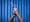 Photograph of a pair of hands firmly holding shut a vaginal speculum. Photographed against a background of blue antibacterial clinical curtains.