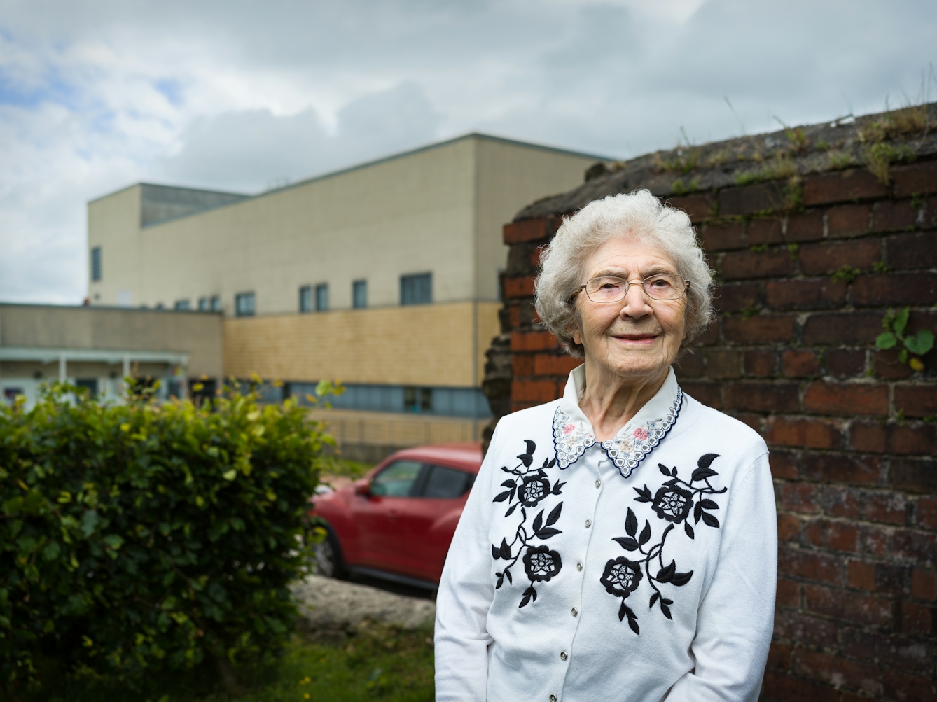 Photographic portrait of Joyce Thompson standing in front of the Royal Blackburn Hospital.