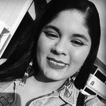 Head and shoulders photograph of a young woman with straight long dark hair, smiling, head tilted.