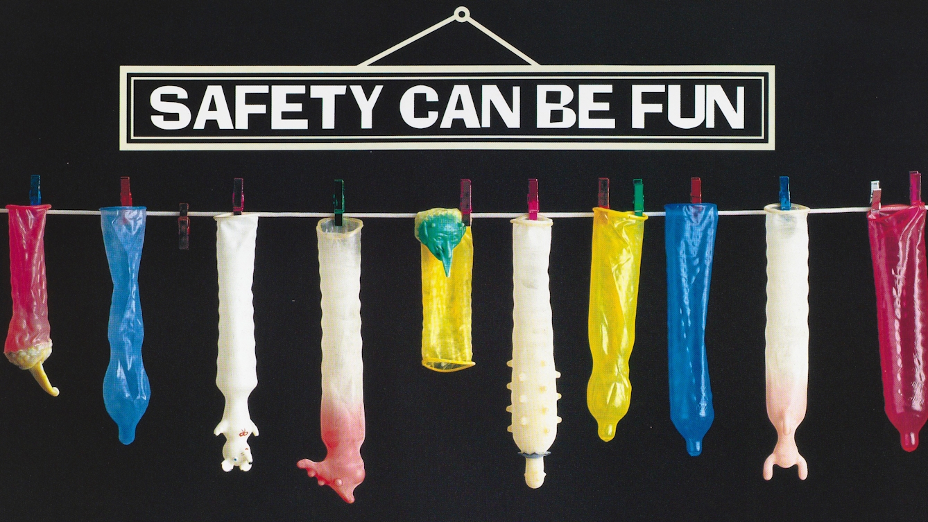 Washing line with various condoms pegged to it and hanging down, with a sign above in bold white against a black background that reads "SAFETY CAN BE FUN"