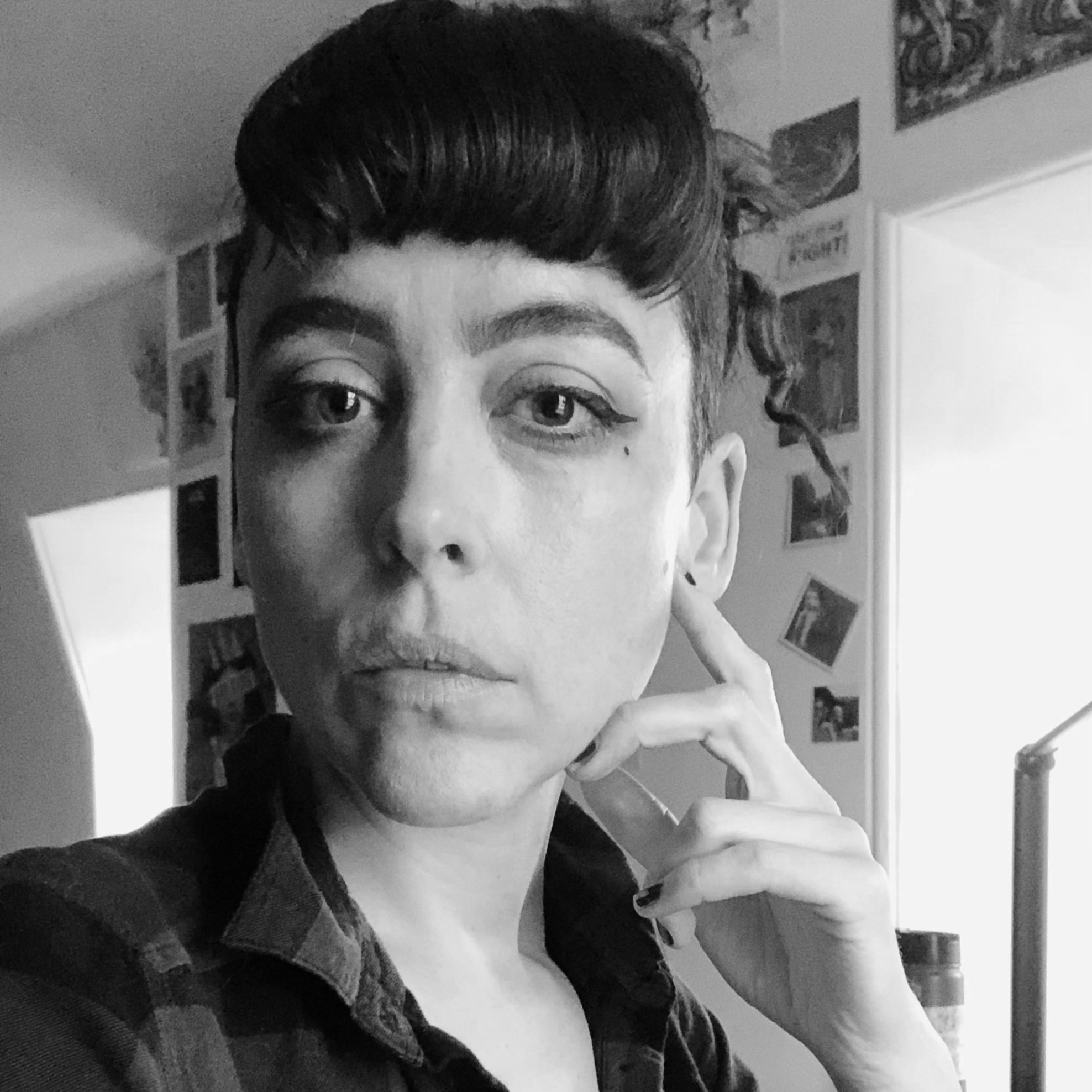 Black and white head and shoulders portrait of Kathryn Briggs who has a thick, brown fringe and is wearing a checked shirt.