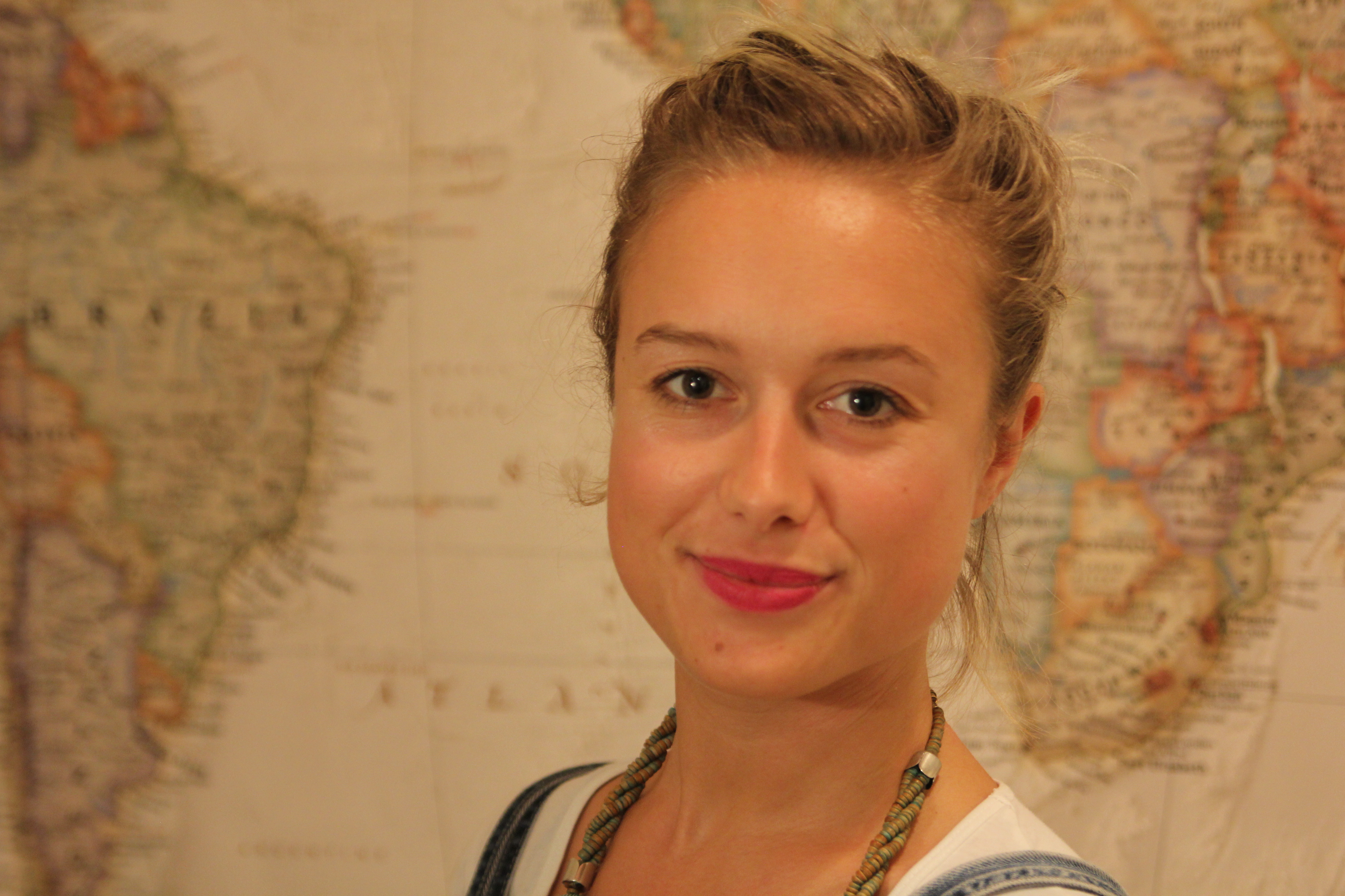 Head and shoulders photo of author Lucy Jones infront of a map of the world