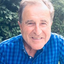 Colour photograph of man wearing a blue checked shirt.