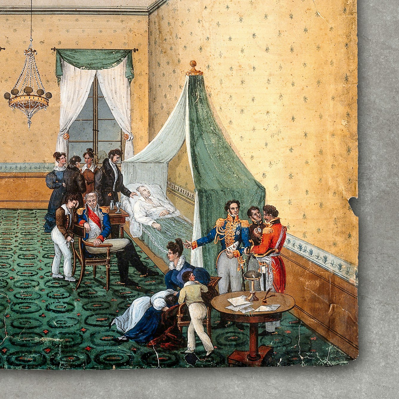 Photograph of a watercolour depicting the death of Napoleon Bonaparte. Napoleon is lying in bed surrounded by 12 people, some wearing military uniform. Three of these people are young children. One of the people stands at Napoleon's head, his hand resting on napoleon's shoulder. The bed is in a large room, with green patterned carpet and yellow wallpaper. A chandelier hangs from the high ceiling. The watercolour has been photographed against a grey concrete background.