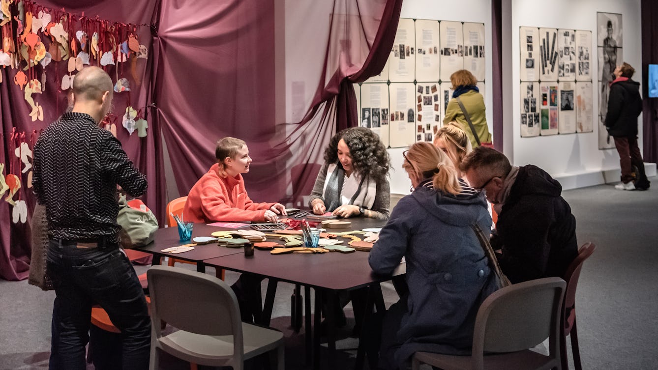 A group of people in conversation around a table in the Misbehaving Bodies exhibition at Wellcome Collection