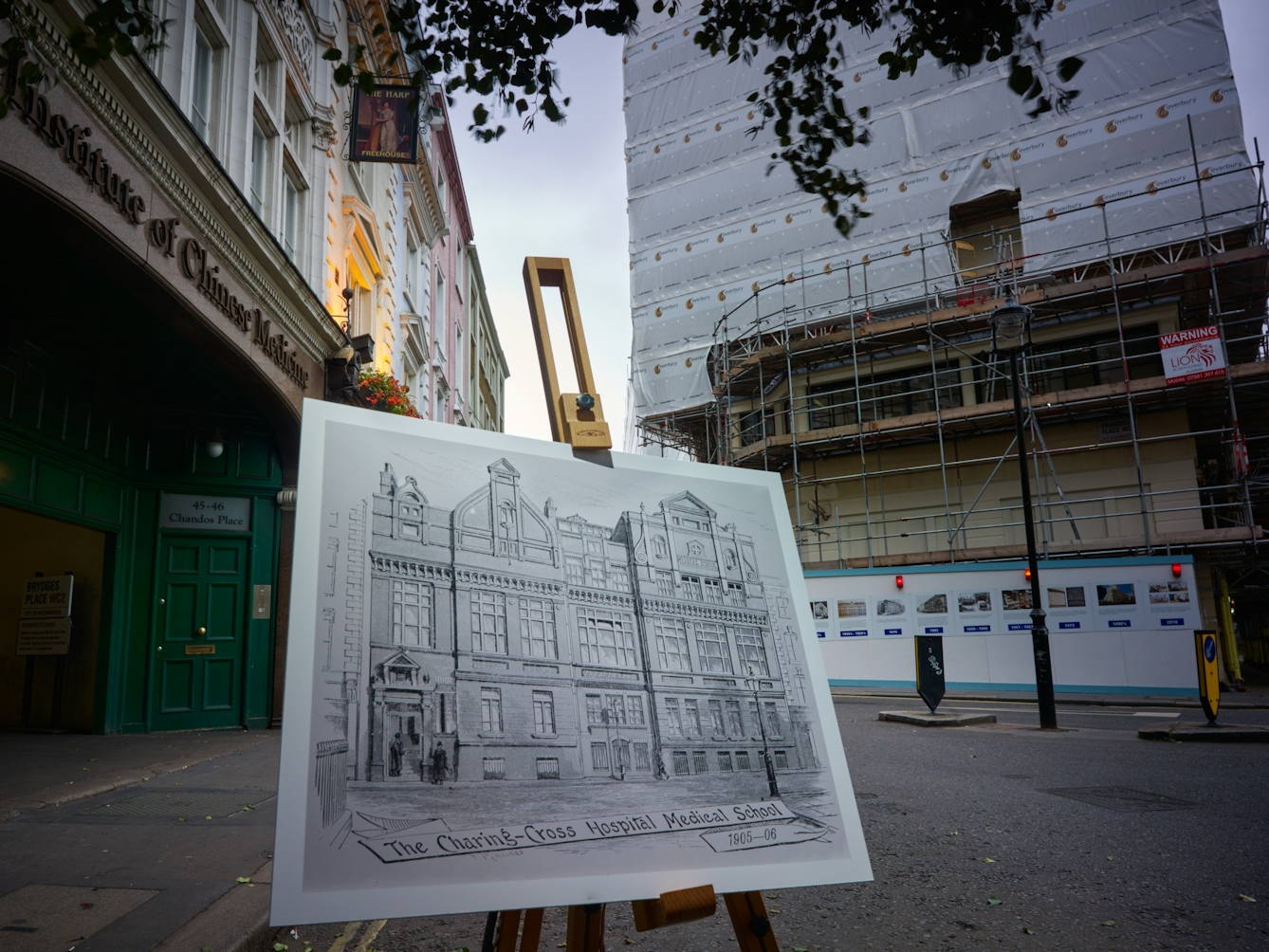 Photograph of the former Charing Cross Hospital with an historical image of the hospital displayed in front of it on a wooden artist's easel.