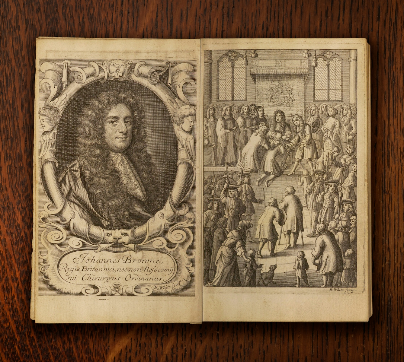 A photograph of an open book against a dark wood background. The pages of the book show two illustrations. To the left is a portrait of Johannes Brown shown with long curly hair and a lace neckerchief. To the right there is a depiction of a crowded official ceremony with the King presented with diseased men who are kneeling in front of him.