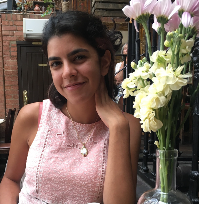 Young woman sitting by a vase of flowers in an outdoor courtyard