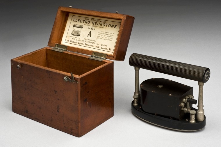 Image of a wooden box next to a black oval piece of metal with a handle on it.