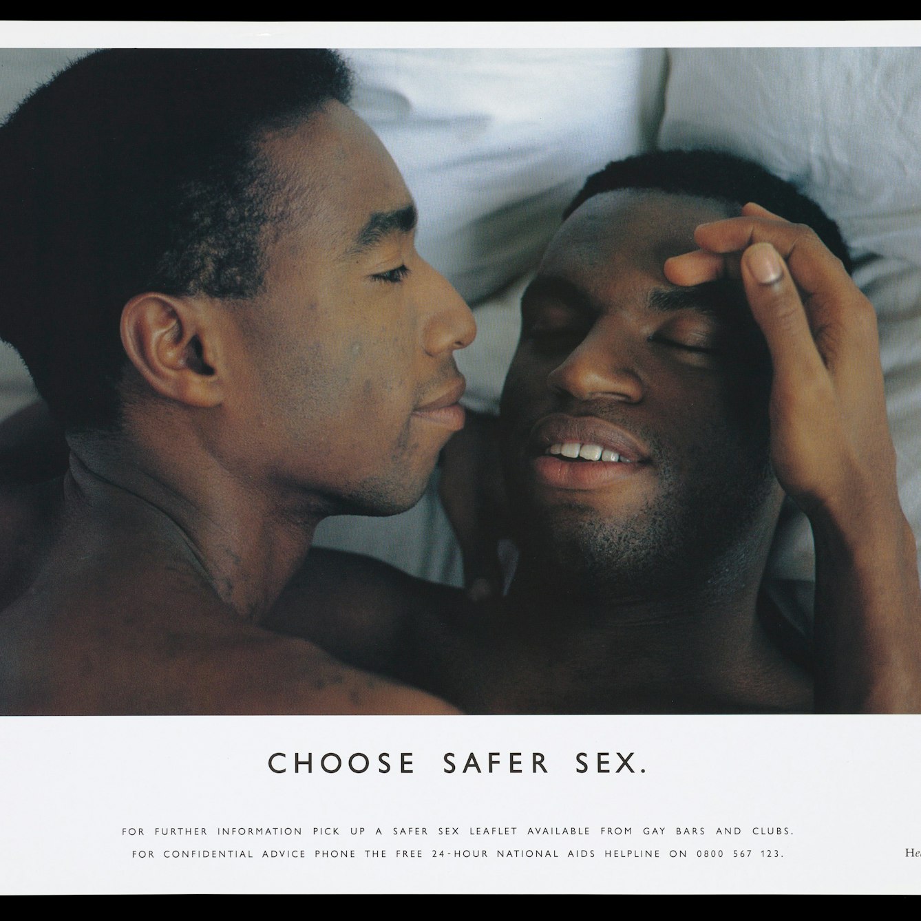 A photograph of two gay black men laying in bed with the headline 'Choose safer sex'.