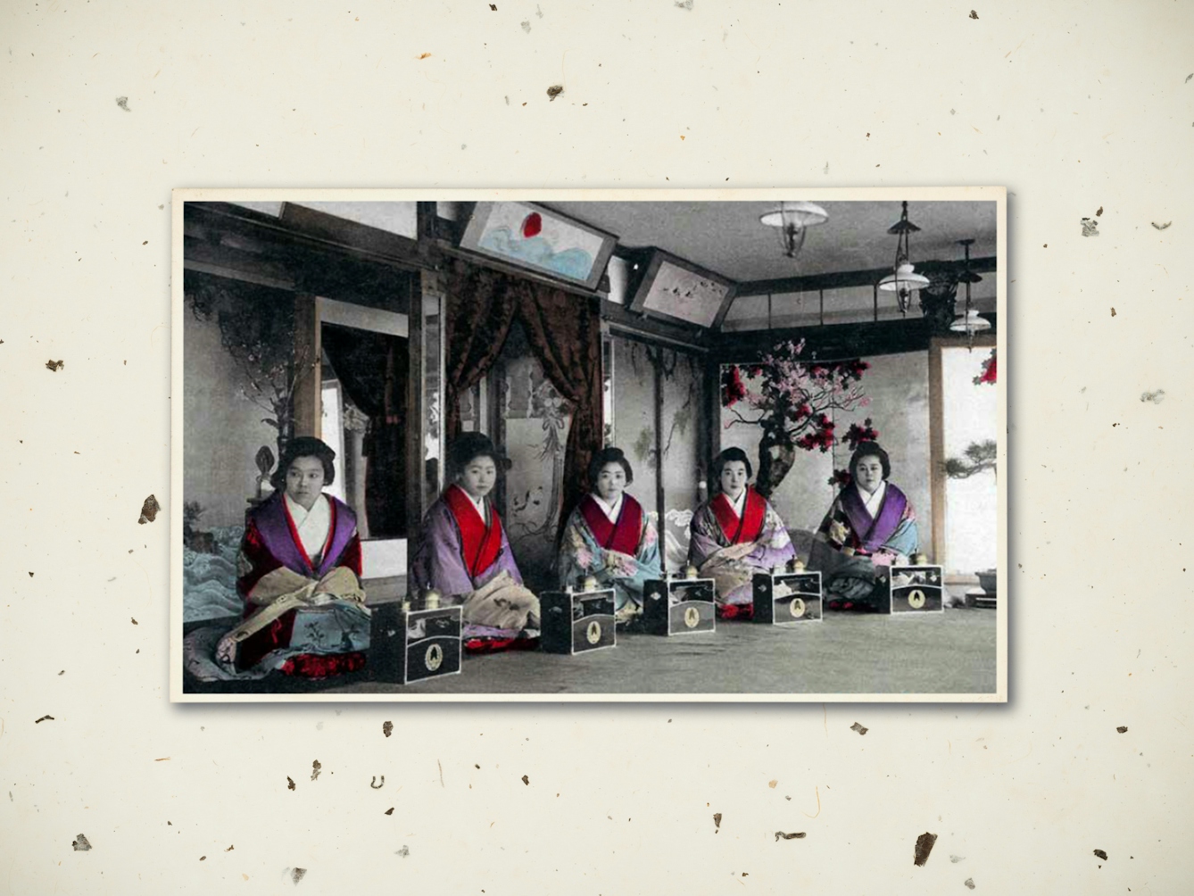 Digital composite image showing a textured rice paper background. Resting on top of the background is an early 20th century black and white photograph showing sex workers of the Yoshiwara, seated behind small table boxes. Their clothes have been hand tinted with colours. Their expressions are blank and sombre. 
