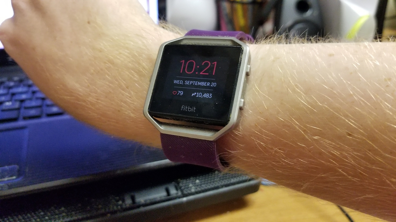 Photograph of an arm wearing a Fitbit Blaze watch showing the time and date, a heart rate of 79 bpm and 10,483 steps.