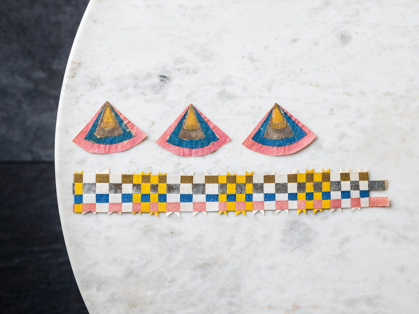 Three pizza slice-shaped pieces of paper jewellery and a woven paper crown-style band.