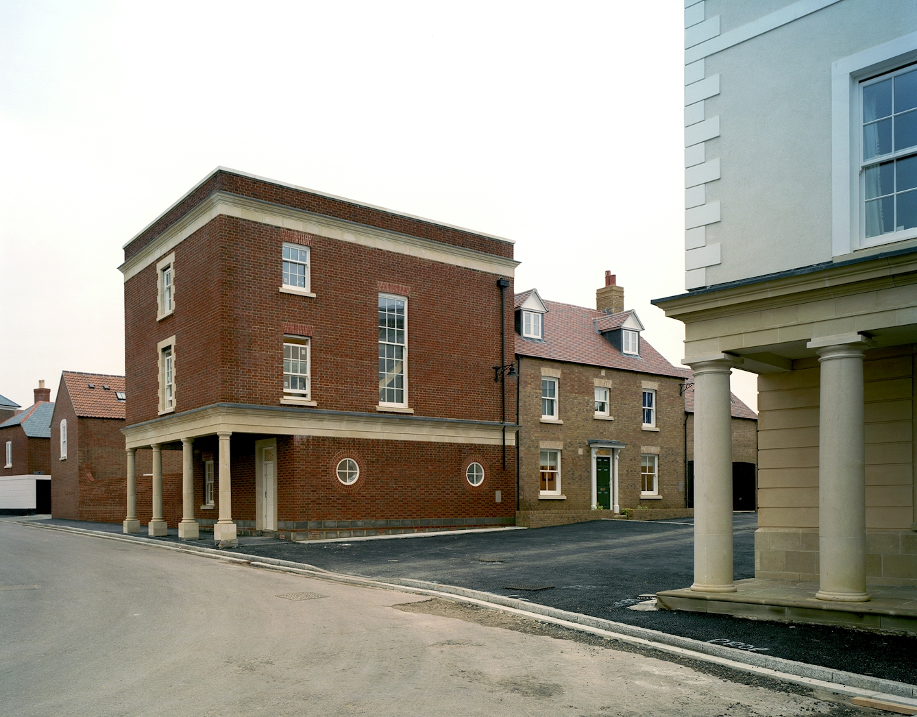 A contemporary photograph taken in Poundbury. Shows streets empty of people and cars, and a purpose-built new boxy houses with old-style columns.
