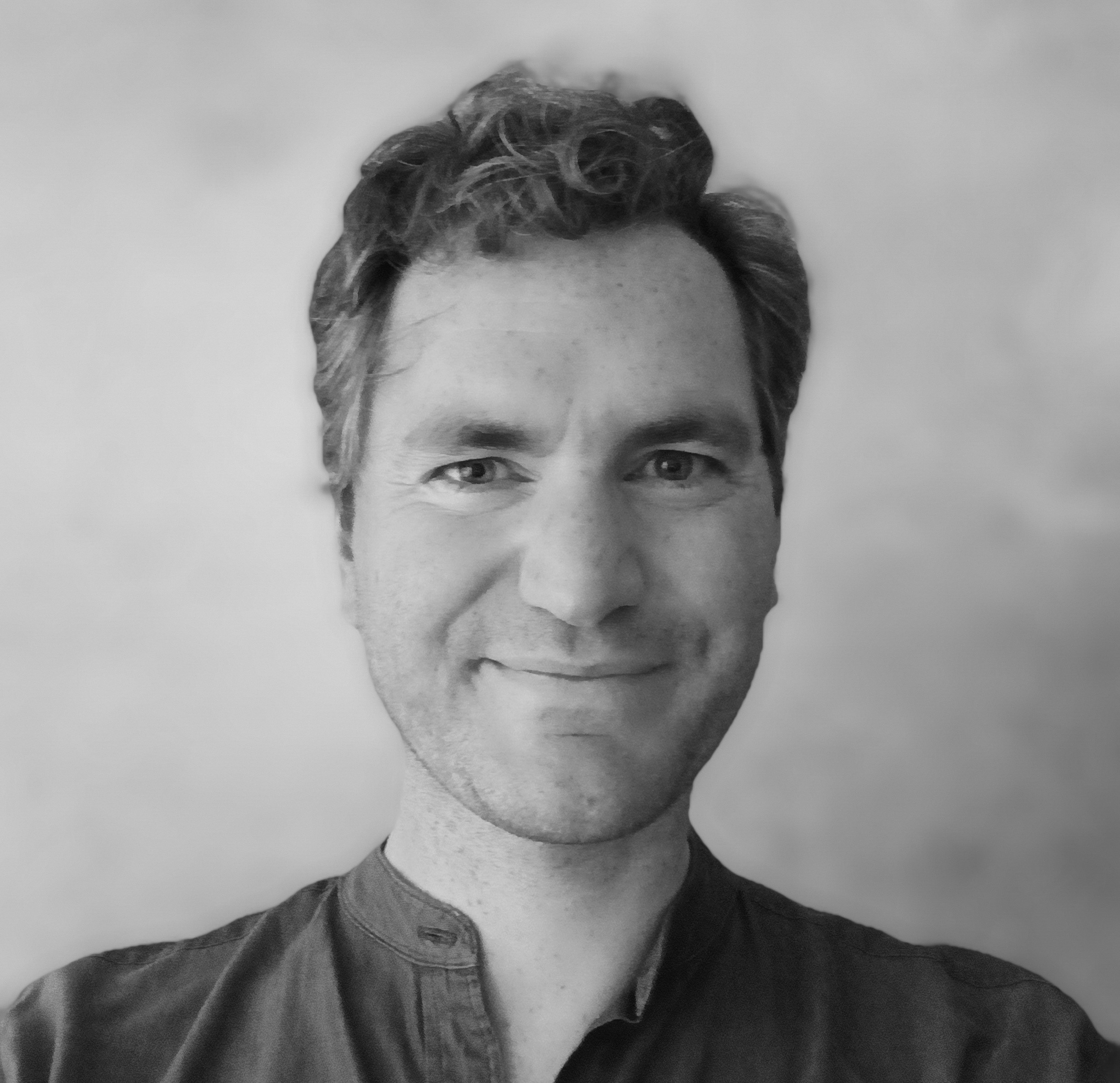 Black and white photograph of a young white man looking straight at the camera and smiling.
