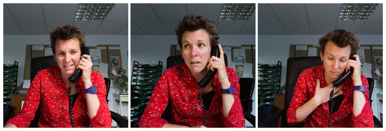 Photographic triptych showing the same woman in each image, sat in an office environment. In the left hand image the woman holds a landline telephone receiver to her left ear, she is smiling slightly. In the middle image she holds the receiver to her left ear and her head is tilted to the left and she is looking out to camera left. In the right hand image she holds the receiver to her left ear, her light hand is clasped to her chest and she is looking down onto the desk.