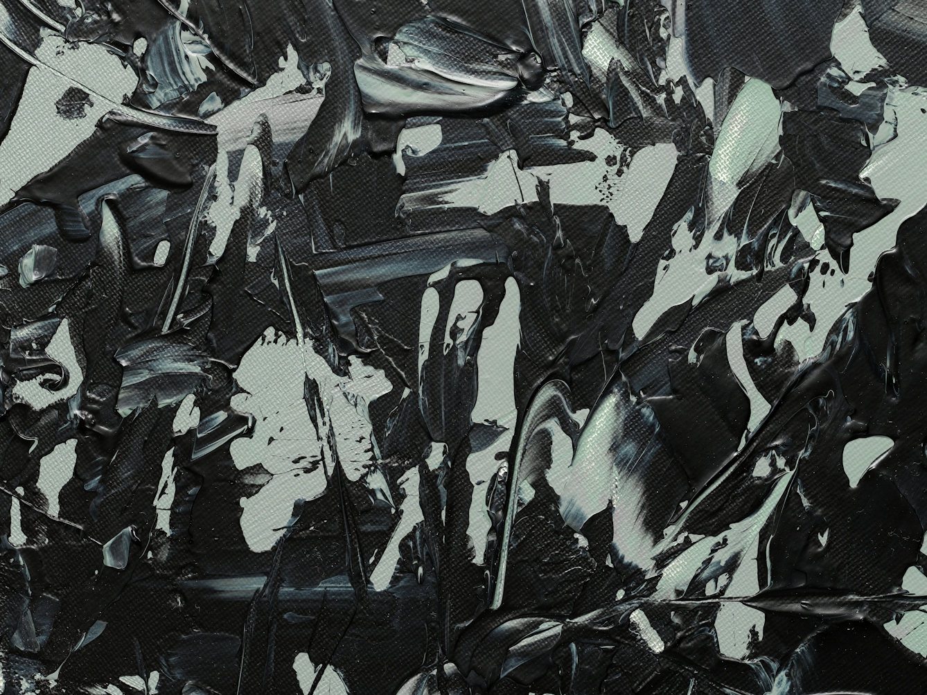 Photograph of close-up detail of a larger abstract expressionist painting on a large circular canvas, titled 'Binaries'. It is predominantly monochrome. The background layer is completely covered with grey and green-grey hues. Textural qualities have been captured in the acrylic paint including impressions made by deep brush strokes and gathered, layered paint. Black expressionist marks, created with a palette knife, scatter across the surface and begin to accumulate towards one side of the canvas. Some marks include waves of banded black and grey. The black marks are reminiscent of a murder of crows, with their onyx wings stretching and taking flight.