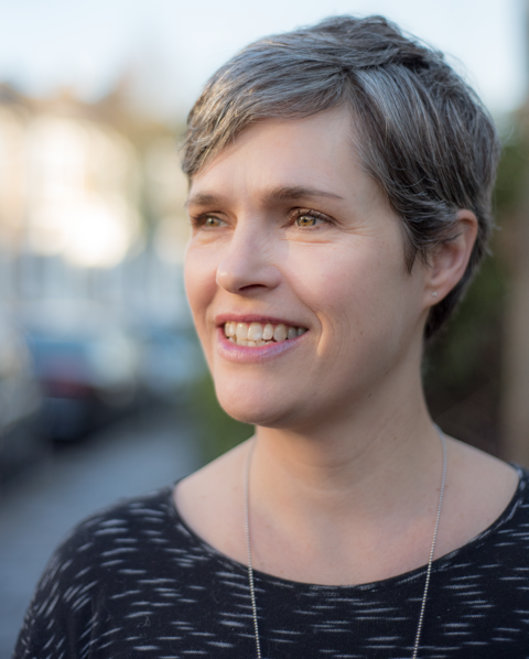 Headshot of Jen Harvie, with short hair, smiling into the distance 