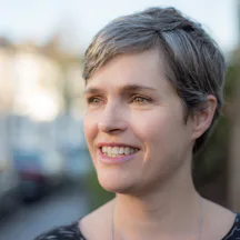 Headshot of Jen Harvie, with short hair, smiling into the distance