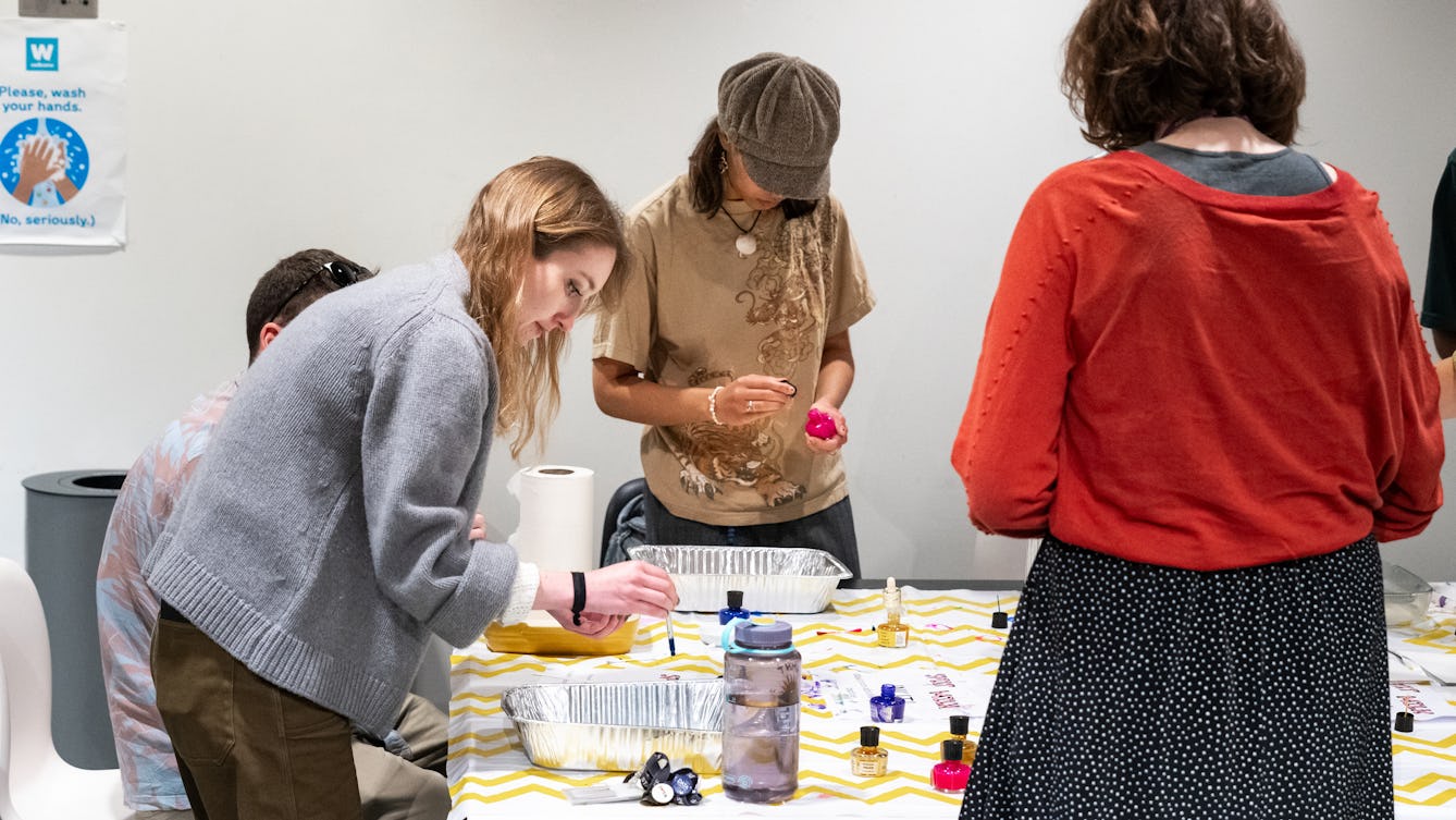 A group of people gathered around a table mixing liquids in trays.