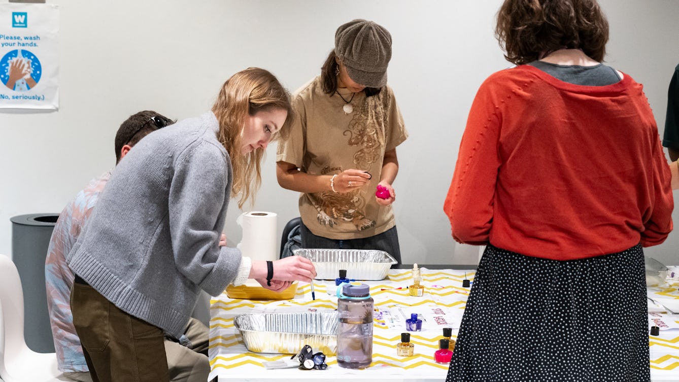 A group of people gathered around a table mixing liquids in trays.