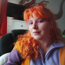 Head and shoulders photo of artist Morrigan with long, curly hair and a fringe.