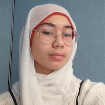 Head and shoulders shot of a person wearing a headscarf and round glasses.