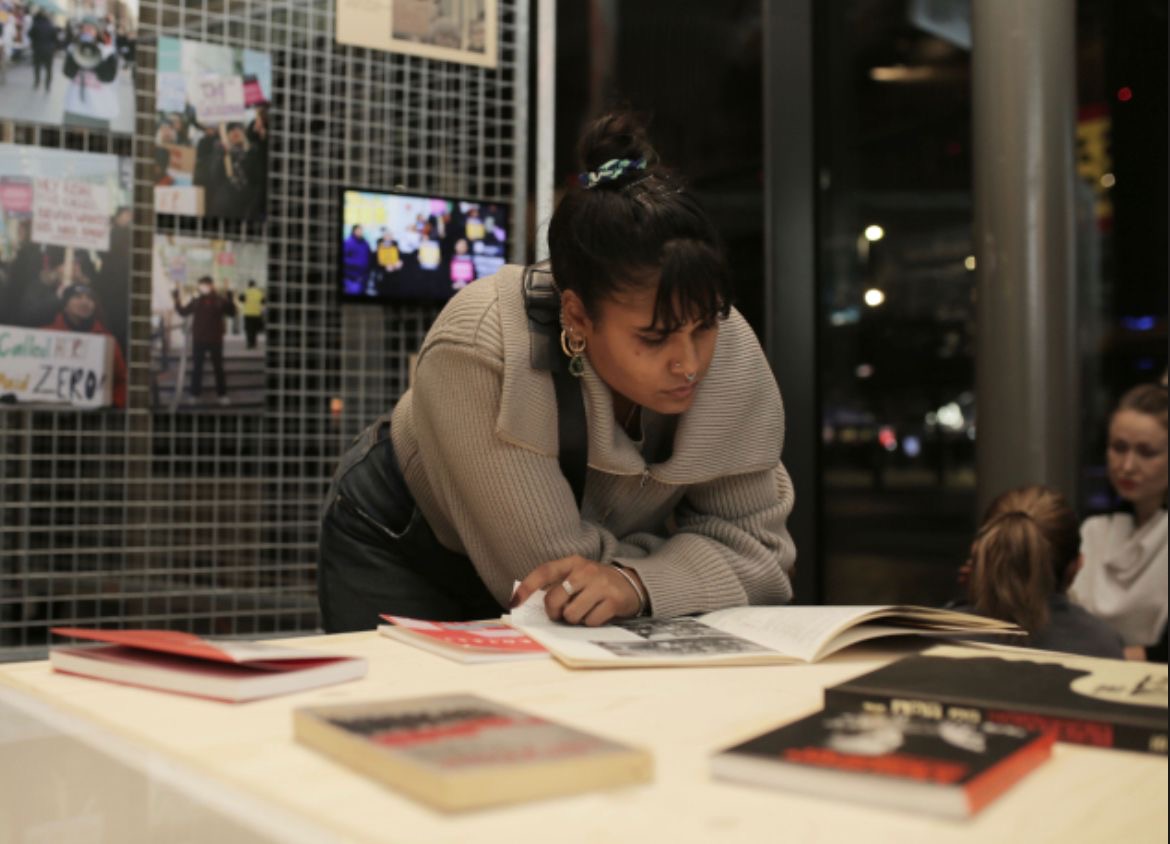 A photo of Vanesha leaning over a table, reading a book. 