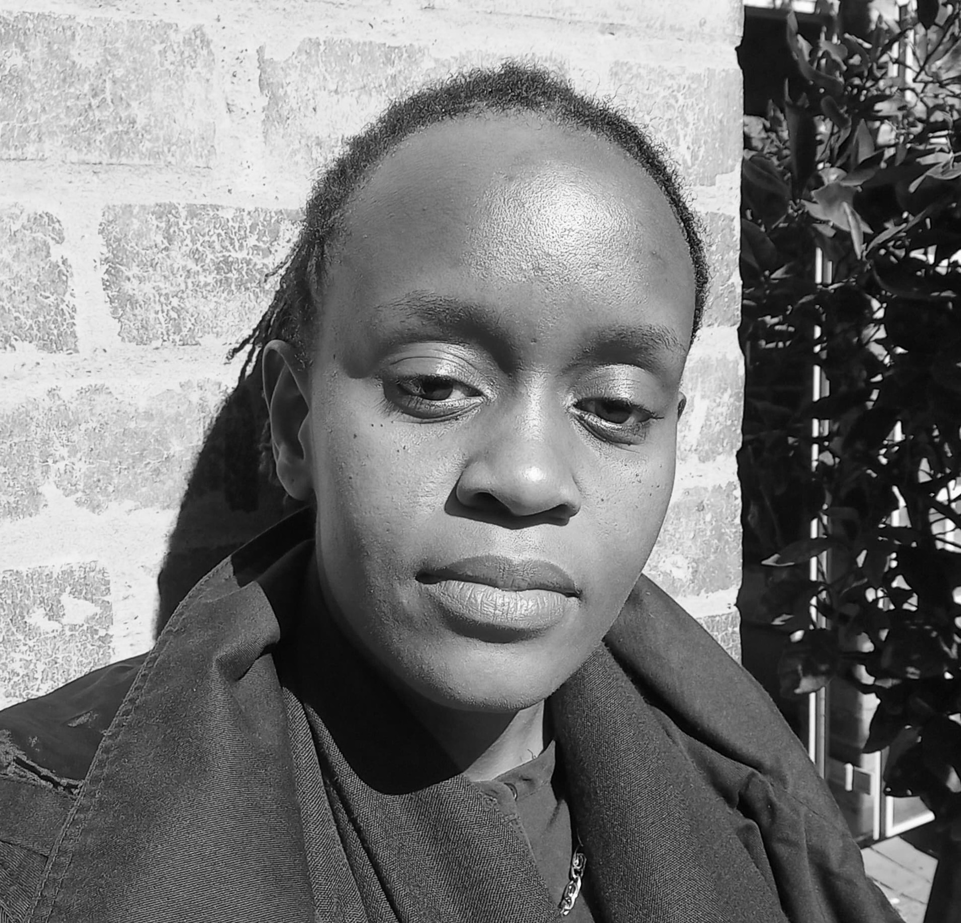 Black and white photograph of the head and shoulders of a young woman with her hair tied back. She is looking directly at the viewer.