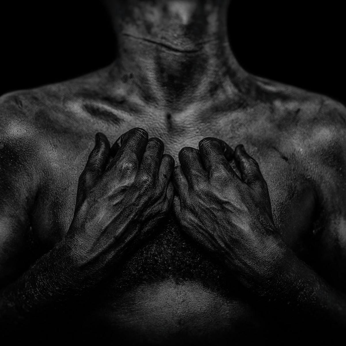 A photograph of a man’s chest and hands. 