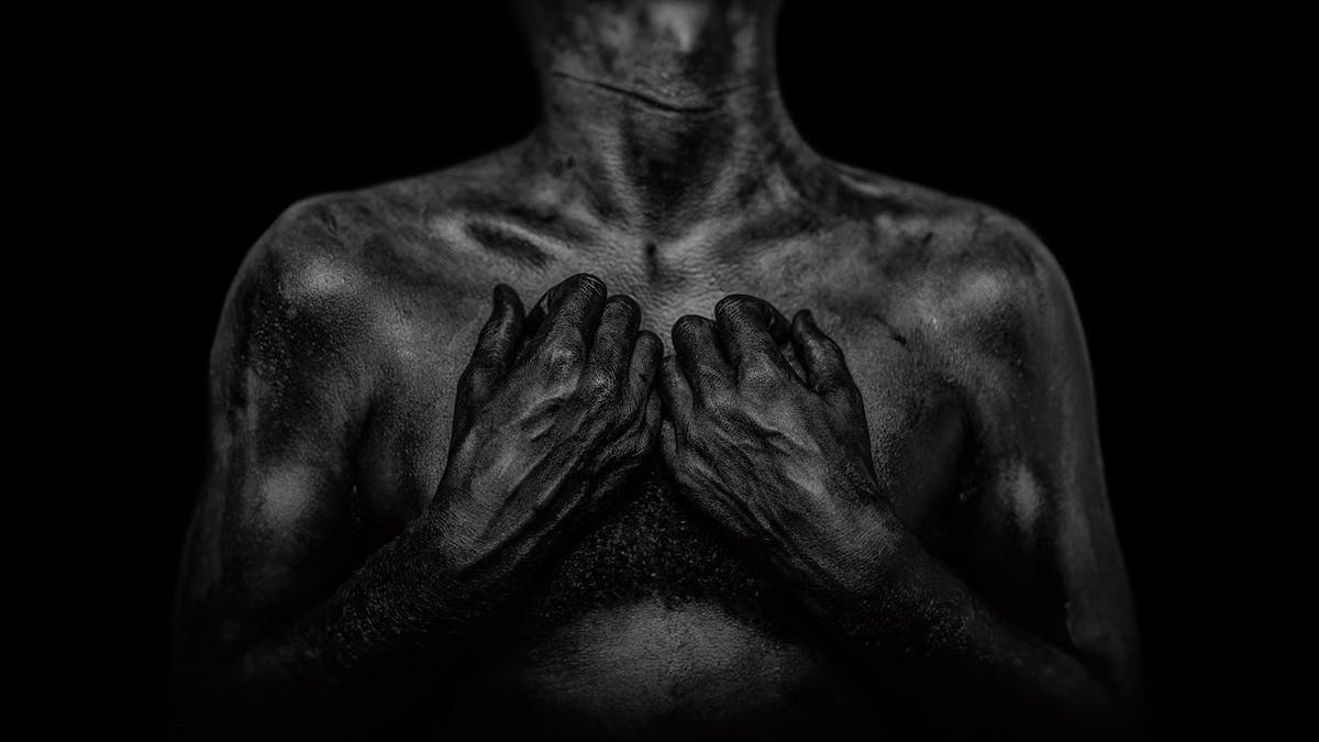 A photograph of a man’s chest and hands. 