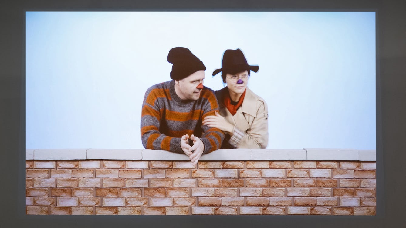 A film still from the film 'What's Left' from the exhibition '1880 THAT'. The still shows the artists Christine Sun Kim and Thomas Mader dressed as two characters called Lefty the Salesman and Ernie from the American TV show ‘Sesame Street’.