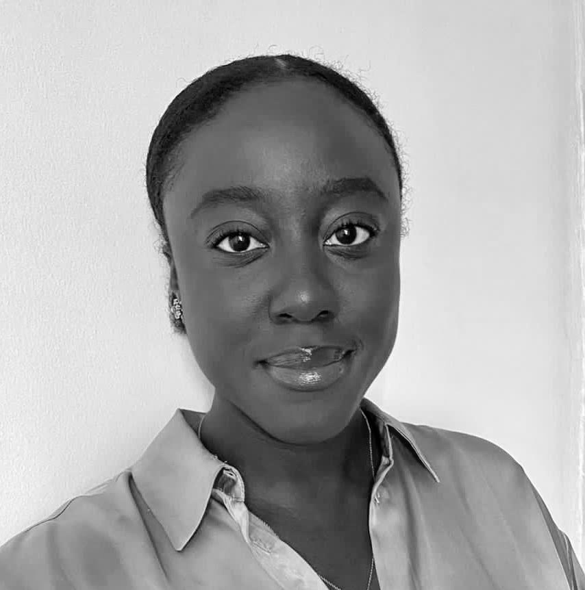 Black and white photograph of the head and shoulders of a young black woman. The woman is looking directly at the camera and smiling.