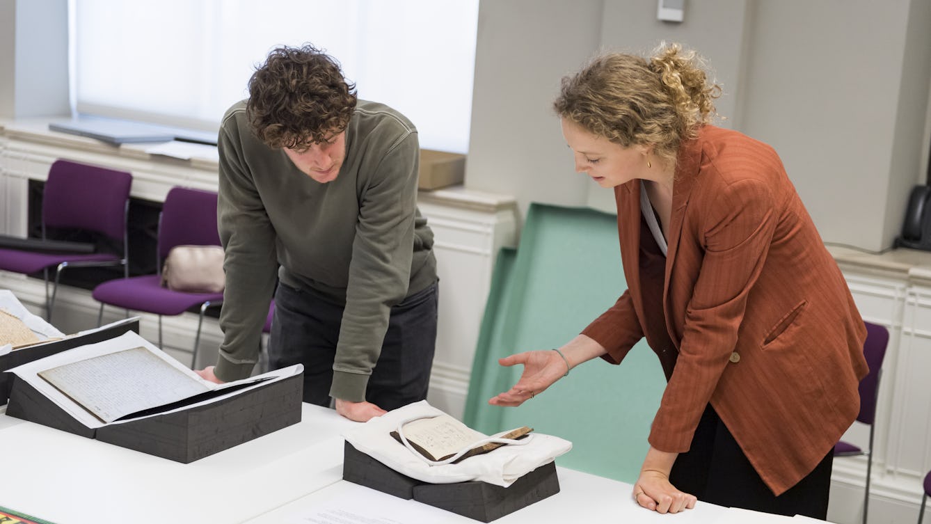 Photo of two people looking down at books displayed on a table.