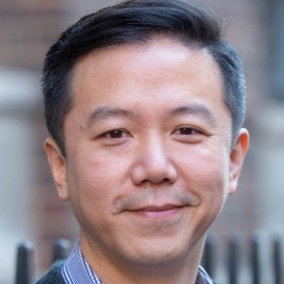 Headshot of a man with short hair smiling and looking to camera