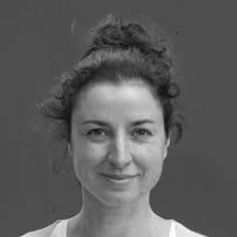 Black and white photo of the head and shoulders of a young woman with her hair in a tight bun. She is smiling and looking directly at the viewer.