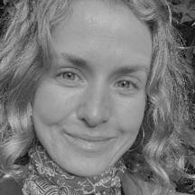 A black and white photo of the face of a young woman with shoulder-length blonde hair. She is smiling and looking directly at the camera.