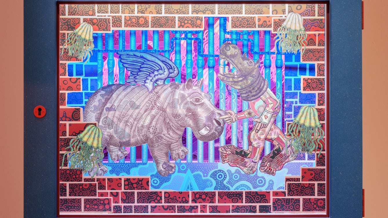Photograph of a diorama called The Hippo Scare. A hippo with wings faces a human figure with a hippo head, both surrounded by floating jellyfish and flowing water.
