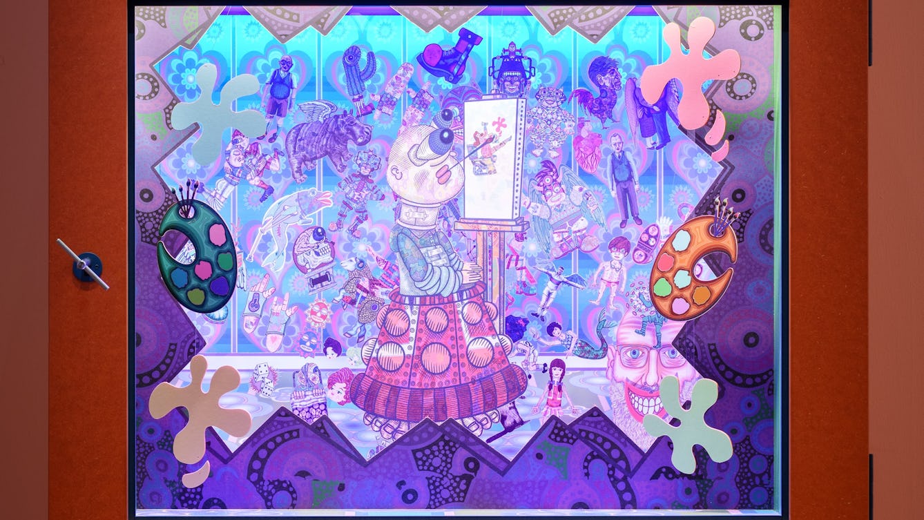 Photograph of a diorama called Painting with My Mouth. A human figure, representing Jason, with a dalek base (a skirt-like structure of plates studded with globes) painting with his mouth surrounded by paint pallets and splashes of paint.