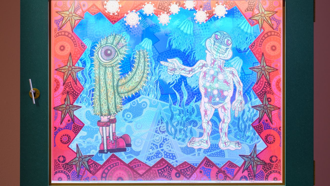 Photograph of a diorama called Painting with My Mouth. A human figure, representing Jason, is pointing towards a spiky cactus figure with a single large eye, wearing calliper boots.