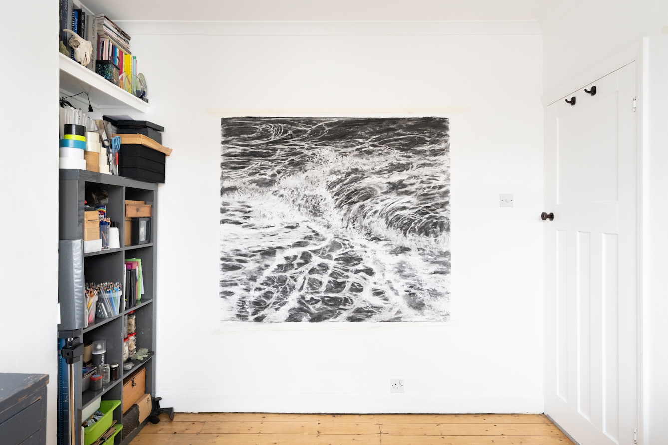 A photograph of the artist Liz Atkin's studio showing a large scale charcoal work on paper.