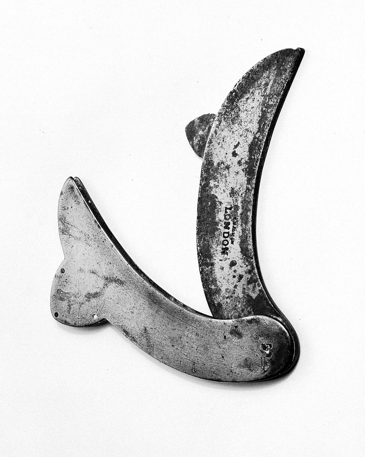 Photograph showing a fleam, which is made of a curved blade that appears to fold back inside a case like a penknife. The bade has a large notch on the outside of the curve. It has London engraved onto it and shows considerable signs of wear and age. 