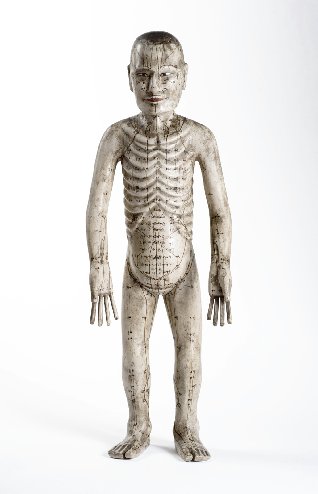 An image of a human figure made from papier mache with acupuncture points marked on it.