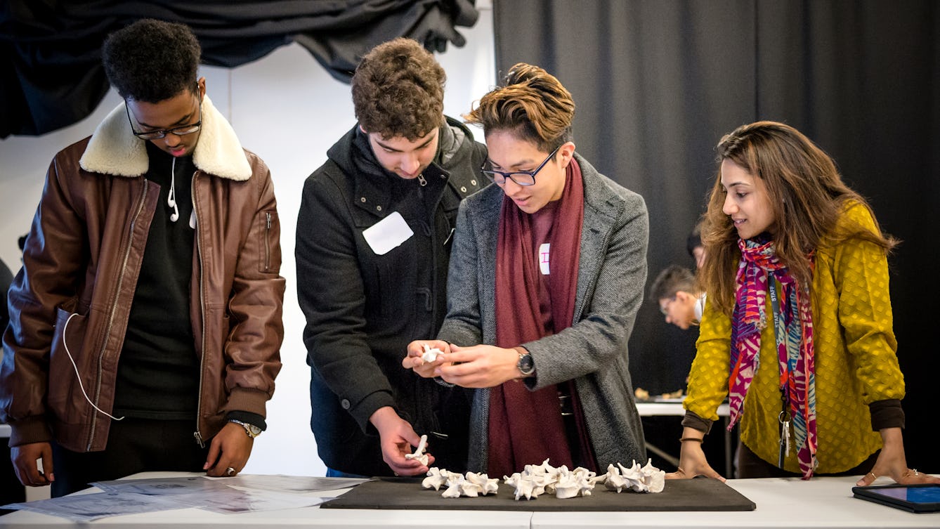 Photograph of four people discussing a skeleton which is laid out on a table in front of them.