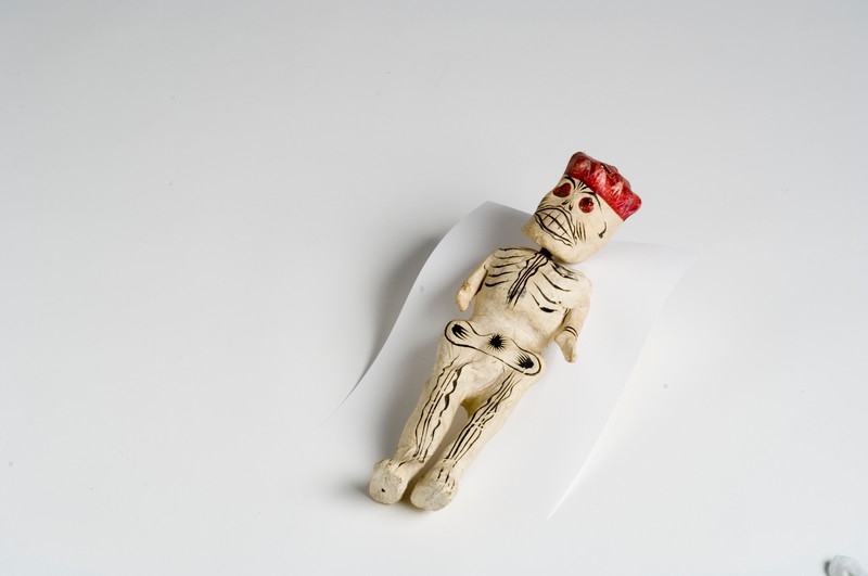 Image of papier-mâché sculpture of a human skeleton in a red hat by a Mexican artist