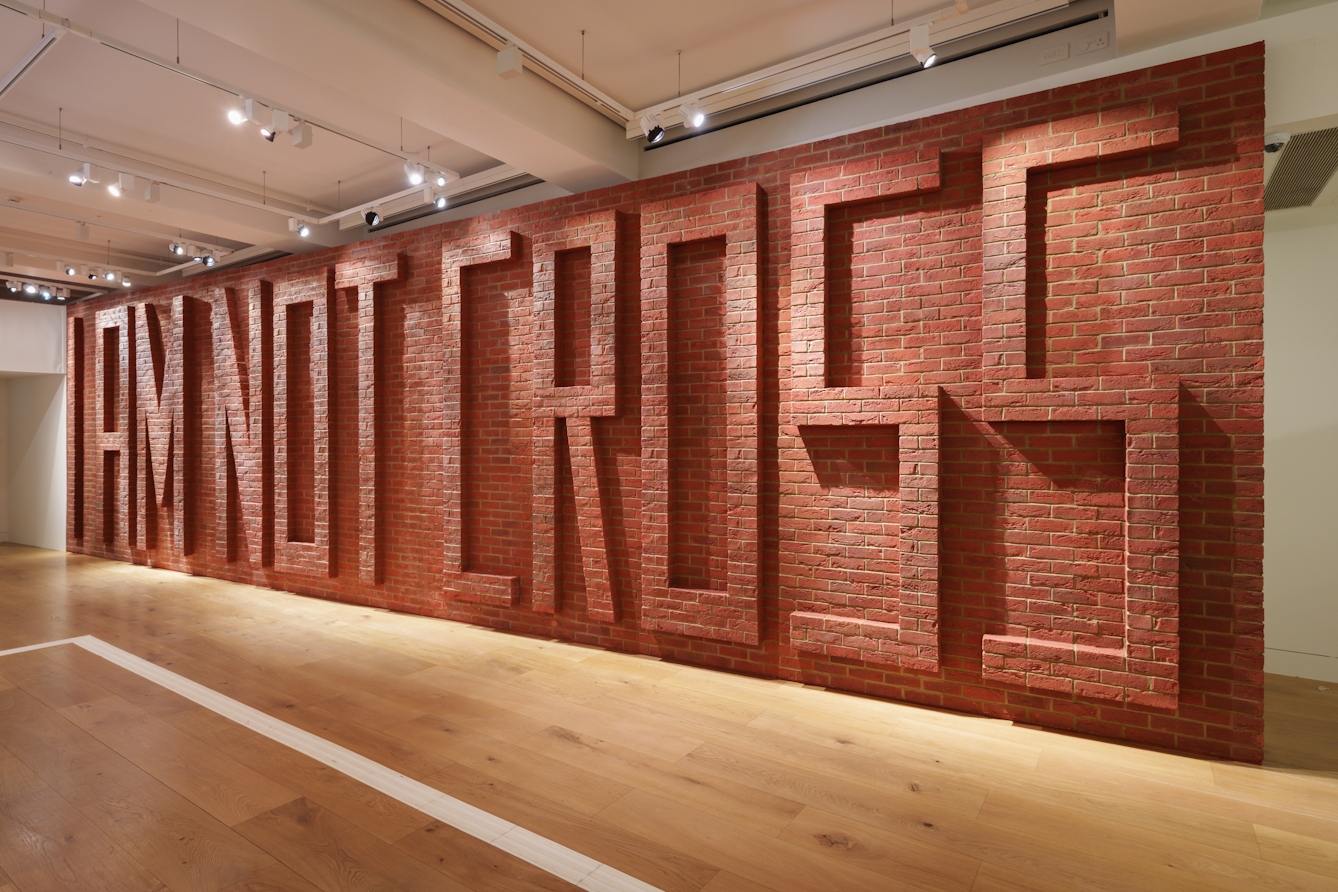A photograph of a large brick wall, in the brickwork there are the words ‘I am not cross’.