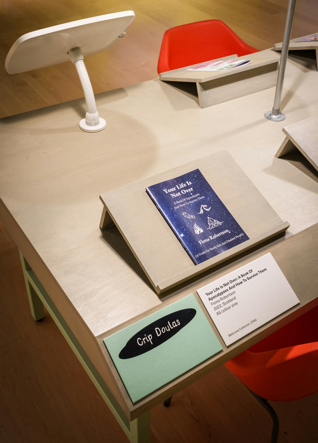 The zine 'Your life is not over' by Fiona Robertson, resting on a plinth in the gallery.