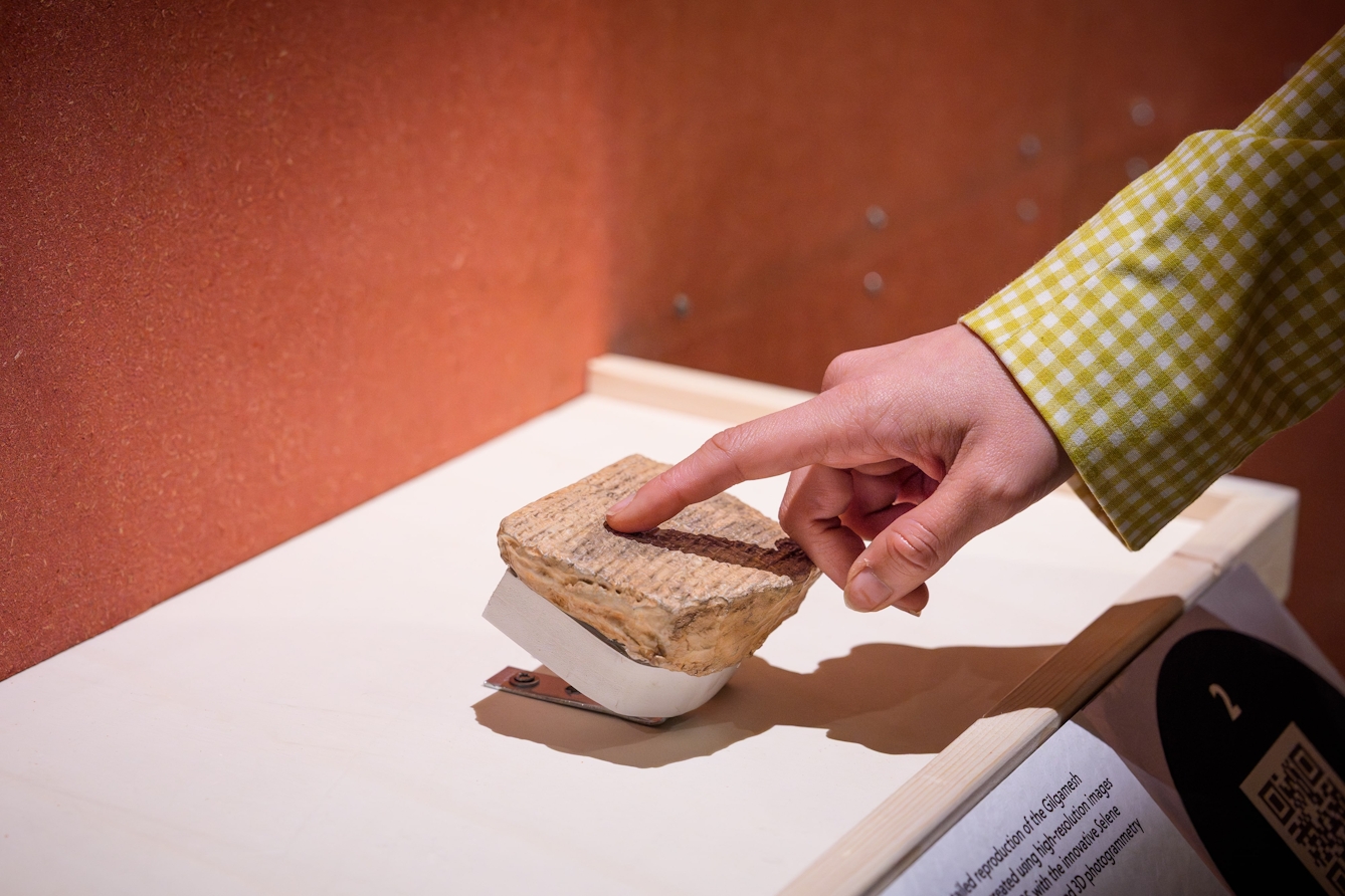 A hand touching a copy of an ancient clay tablet.